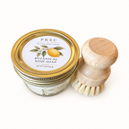 PRSC Botanical Dish Soap in a clear glass jar with a gold metal lid, shown next to a small wooden-handled dish brush on a clean white background.
